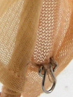 Detalle de una tela de trama abierta con un gancho metálico.